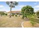 Expansive backyard featuring a screened-in lanai, tropical trees, and well-maintained landscaping at 1805 Granville Ln, Sun City Center, FL 33573