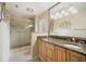 Bathroom with dual sinks, granite counters, and a tiled shower with a glass door at 1805 Granville Ln, Sun City Center, FL 33573