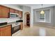 Kitchen with stainless steel oven and microwave, wood cabinets, breakfast nook, and laundry in doorway at 21744 Waverly Shores Ln, Land O Lakes, FL 34637