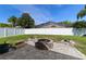 Backyard features a stone fire pit and enclosed patio surrounded by a white fence and manicured lawn at 26850 Middleground Loop, Wesley Chapel, FL 33544