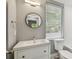 Bright bathroom with a modern vanity, round mirror, and a view of the backyard at 3411 N 12Th St, Tampa, FL 33605