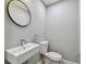 Modern half-bathroom with a sleek sink, round mirror, and gray walls at 3411 N 12Th St, Tampa, FL 33605