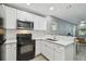 Bright kitchen with white cabinets, modern appliances, and view of the living room at 3411 N 12Th St, Tampa, FL 33605