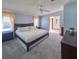 A spacious main bedroom with a large bed, gray carpet, and a view into the main bathroom at 34150 Estates Ln, Wesley Chapel, FL 33543