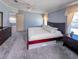 A spacious main bedroom with a large bed, gray carpet, and blue walls at 34150 Estates Ln, Wesley Chapel, FL 33543