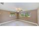 Bright bedroom featuring tile floors, neutral paint, baseboard trim, two windows, and a ceiling fan at 3572 Pocahontas Dr, Largo, FL 33774