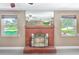 Detailed view of the red brick fireplace, windows, and a glimpse into the kitchen at 3572 Pocahontas Dr, Largo, FL 33774
