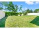 Spacious grassy backyard, partially enclosed by a white fence and shrubbery at 4247 Balmoral Ct, Wesley Chapel, FL 33543