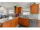 Bright kitchen featuring wooden cabinets, granite countertops, stainless steel dishwasher, and tile backsplash at 4247 Balmoral Ct, Wesley Chapel, FL 33543