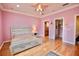 Spacious bedroom featuring pink walls, hardwood floors, a ceiling fan, and an attached closet at 441 Lucerne Ave, Tampa, FL 33606