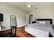 Well-lit bedroom featuring hardwood floors, a ceiling fan, and a comfortable seating area with ample lighting at 5460 Millbrook Way, Palm Harbor, FL 34685