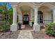 Elegant front entrance with stately columns, a brick walkway, and beautiful landscaping at 5460 Millbrook Way, Palm Harbor, FL 34685