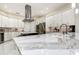 Modern kitchen boasts white cabinets, stainless steel appliances, and a large island with marble countertops at 5460 Millbrook Way, Palm Harbor, FL 34685