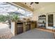Outdoor kitchen with BBQ, sink, mini-refrigerator, and bar seating at 5460 Millbrook Way, Palm Harbor, FL 34685