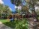 Community playground with swings, slides, and a picnic area, set in a lush green landscape with blue skies above at 5460 Millbrook Way, Palm Harbor, FL 34685