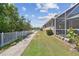 Beautiful backyard featuring a sidewalk, white fence, manicured lawn, and screened-in porch for relaxing and entertaining at 5702 Tides Pl, Apollo Beach, FL 33572