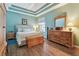 Comfortable bedroom with tray ceiling, wood floors, and dresser at 5702 Tides Pl, Apollo Beach, FL 33572
