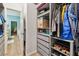 Walk-in closet with custom shelving and drawers, adjacent to bathroom and bedroom with wood floors at 5702 Tides Pl, Apollo Beach, FL 33572