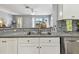 Bright kitchen featuring granite countertops, stainless steel sink, white cabinetry, and a mosaic backsplash at 5702 Tides Pl, Apollo Beach, FL 33572