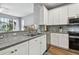 Well-lit kitchen features white cabinets, stainless steel appliances, mosaic backsplash, and granite countertops at 5702 Tides Pl, Apollo Beach, FL 33572