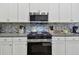 Modern kitchen showcasing stainless steel appliances, white cabinets, granite counters, and mosaic backsplash at 5702 Tides Pl, Apollo Beach, FL 33572