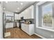 Bright kitchen with stainless steel appliances, white cabinets, granite countertops, and warm wood-look flooring at 5702 Tides Pl, Apollo Beach, FL 33572