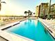 Large community pool with lounge chairs and building in background, with a view of the water at 690 Island Way # 707, Clearwater Beach, FL 33767