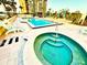 Community pool and hot tub surrounded by lounge chairs and lush landscaping, with the building in the background at 690 Island Way # 707, Clearwater Beach, FL 33767