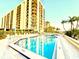 Outdoor swimming pool surrounded by lounge chairs at a condo building with beautiful landscaping at 690 Island Way # 707, Clearwater Beach, FL 33767