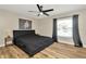 Bedroom featuring wood floors, a black bed set, ceiling fan and a large window at 7041 Lexington Cir, Brooksville, FL 34602