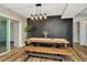 Open dining space featuring modern lighting fixture, rustic table with benches and sleek, dark accent wall at 7041 Lexington Cir, Brooksville, FL 34602