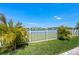 Lush backyard with vibrant landscaping, a serene waterfront view, and a secure white picket fence at 8580 Ivy Stark Blvd, Wesley Chapel, FL 33545