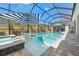 Screened-in pool with a tanning ledge, playful decor, and comfortable lounge furniture under a blue and white striped umbrella at 8580 Ivy Stark Blvd, Wesley Chapel, FL 33545