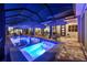 Screened-in pool featuring blue underwater lights, spa, striped umbrellas, lounge chairs, and outdoor dining at 8580 Ivy Stark Blvd, Wesley Chapel, FL 33545