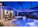 Backyard patio with a screened-in pool, spa, lounge chairs and dining area at 8580 Ivy Stark Blvd, Wesley Chapel, FL 33545