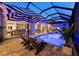 Screened-in pool area featuring blue underwater lights, striped umbrellas, lounge chairs, and outdoor dining at 8580 Ivy Stark Blvd, Wesley Chapel, FL 33545
