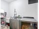 Modern laundry room featuring Whirlpool washer and dryer, utility sink, and shelving at 917 W Alfred St, Tampa, FL 33603