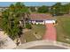 Aerial view of a well-maintained home with mature landscaping and a distinctive red driveway in a peaceful neighborhood at 103 El Turco Ct, Sun City Center, FL 33573