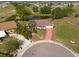 Expansive aerial view of a single-story home with mature landscaping, a red brick driveway and views of a pond at 103 El Turco Ct, Sun City Center, FL 33573