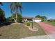 Beautiful home with well manicured landscaping, a lamp post, and a decorative red driveway leading to a two-car garage at 103 El Turco Ct, Sun City Center, FL 33573