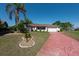 Inviting home featuring a well-maintained lawn, lush landscaping, and a distinctive red-painted driveway at 103 El Turco Ct, Sun City Center, FL 33573