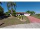 Lovely home boasting mature landscaping, a lamp post, and a striking red driveway leading to a two-car garage at 103 El Turco Ct, Sun City Center, FL 33573