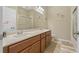 Bathroom featuring double sink vanity, framed mirror, and shower-tub combo with sliding glass doors at 10734 Breaking Rocks Dr, Tampa, FL 33647