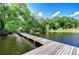 Long wooden dock extending into a picturesque lake with lush foliage around the banks at 13329 N Armenia Ave, Tampa, FL 33613
