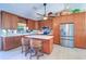 Well-lit kitchen with stainless steel refrigerator, ample cabinetry, and a functional center island with seating at 16247 Fringe Tree Dr, Spring Hill, FL 34610