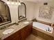 Bright bathroom featuring double vanity, granite counters, soaking tub, and decorative mirror at 1720 Lighthouse S Ter # 8, South Pasadena, FL 33707