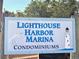 A welcome sign for Lighthouse Harbor Marina Condominiums featuring a lighthouse and a great egret at 1720 Lighthouse S Ter # 8, South Pasadena, FL 33707