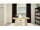 Bright home office featuring a light wood desk, white chair, black curtains, and shelving unit with decor at 1814 Tropical Oasis Ave, Plant City, FL 33565
