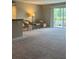 Carpeted living room featuring wicker chairs, lamp, table, and a sliding glass door leading to the balcony at 2583 Countryside Blvd # 3102, Clearwater, FL 33761