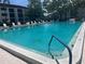 Large, sparkling community pool surrounded by lounge chairs at 2583 Countryside Blvd # 3102, Clearwater, FL 33761
